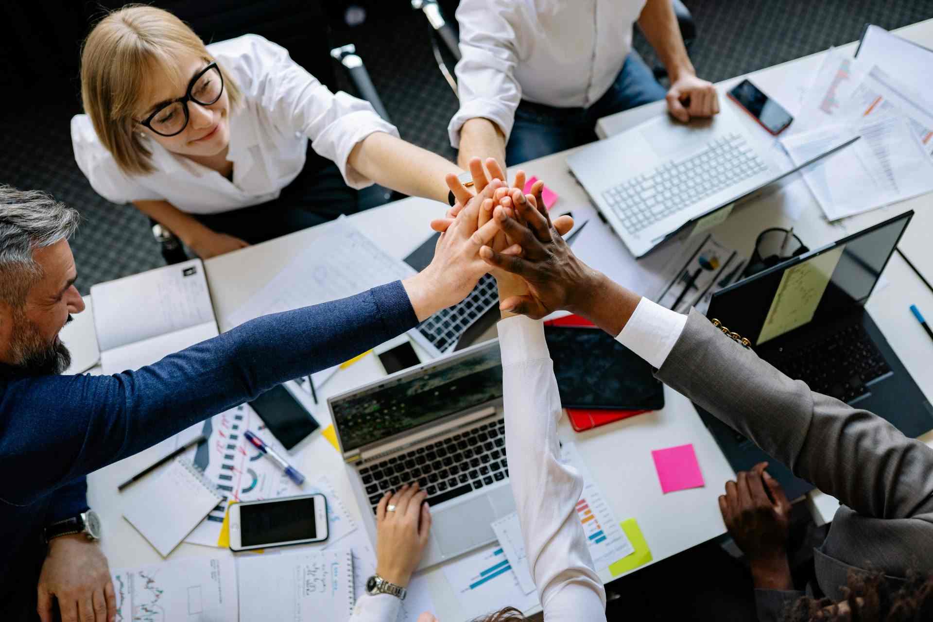 Eine Gruppe von Fachleuten aus verschiedenen Bereichen feiert einen gemeinsamen Arbeitsbereich mit High-Fives.